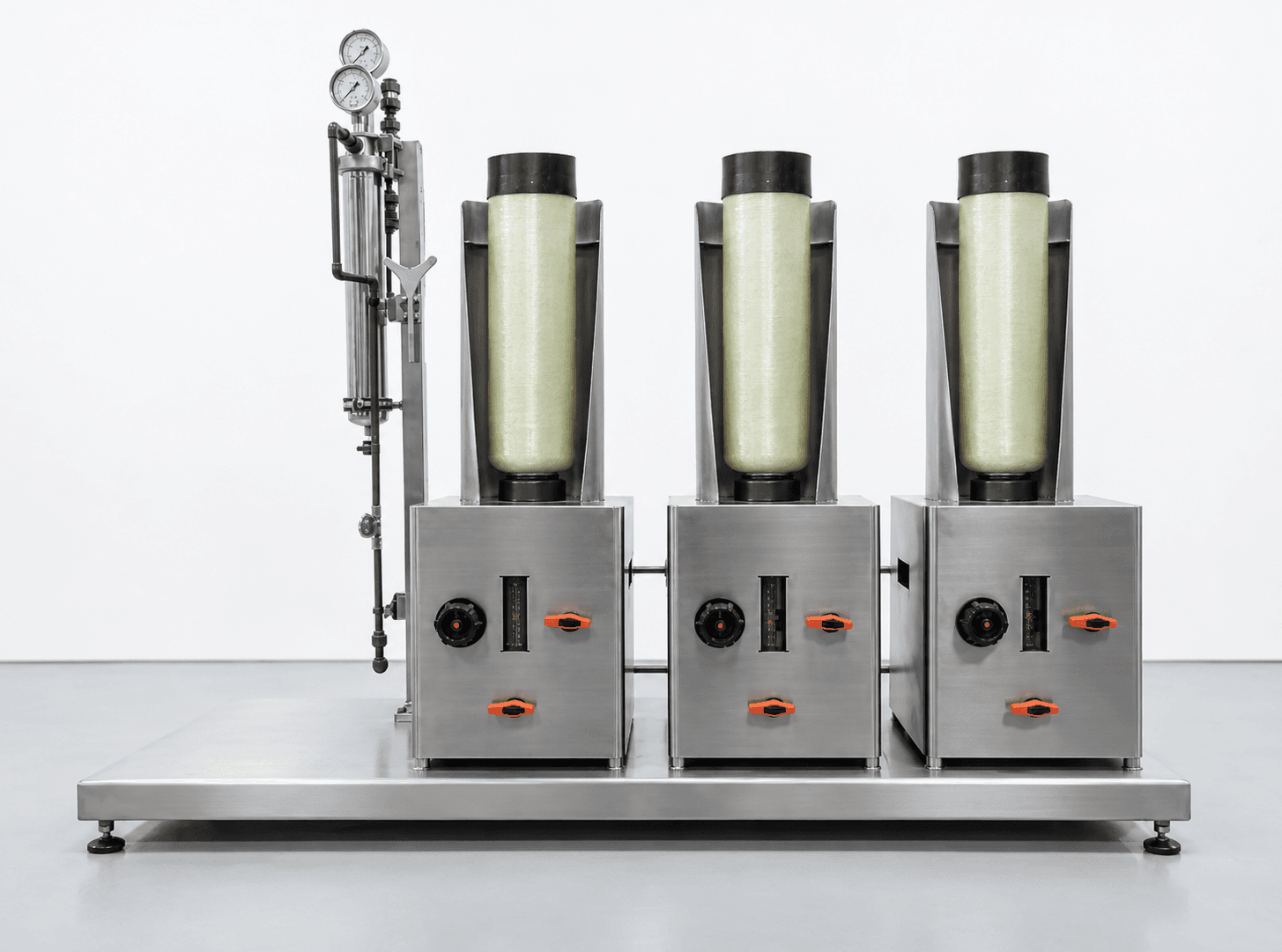 Installed three-column recovery system on a stainless steel skid, with pale-green columns in open protective shields, orange valve handles on each cabinet, and pressure gauges on the left-hand piping assembly