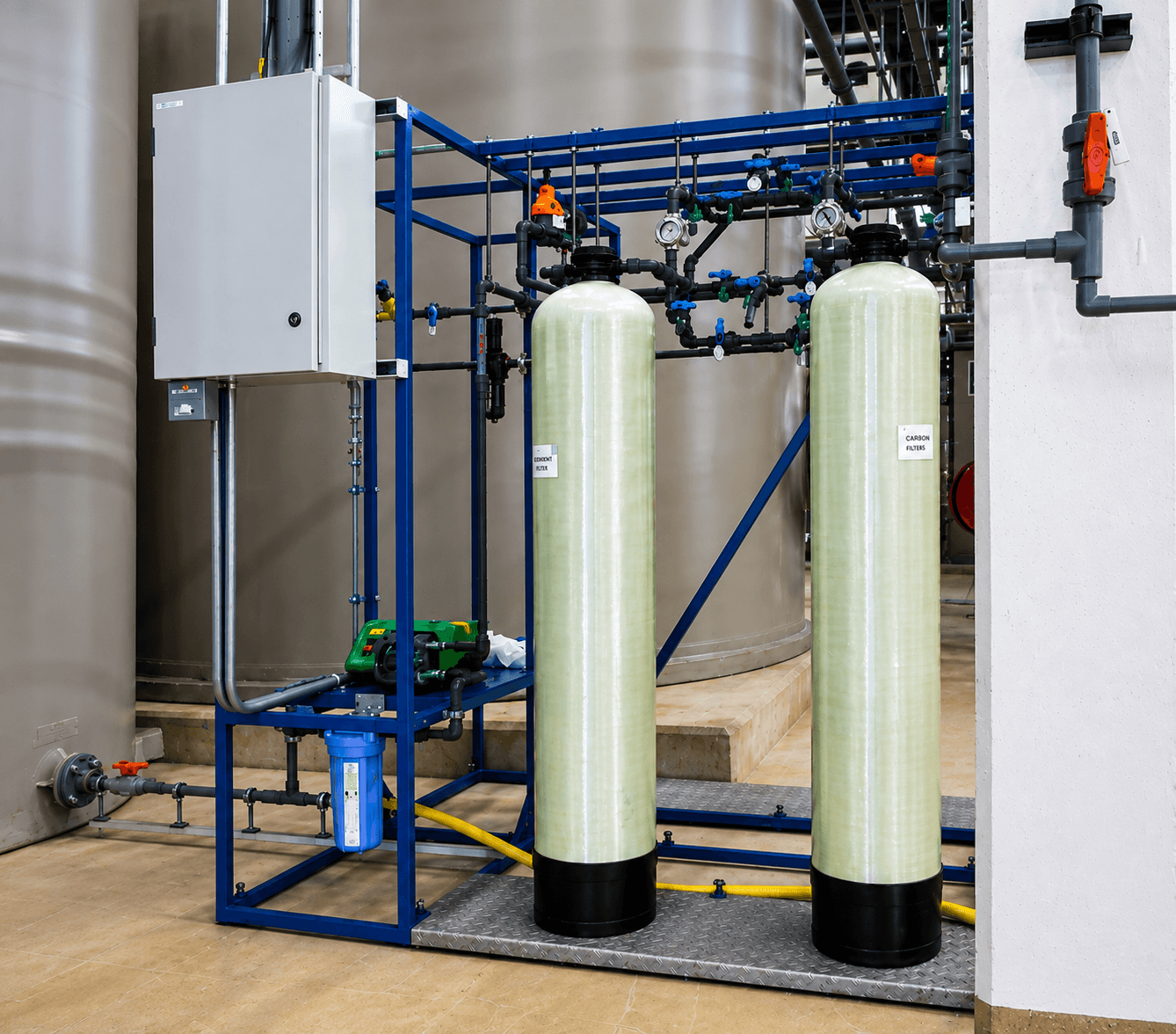 Twin pale-green column system on a blue skid frame with grey control panel, piping and pressure gauges in an industrial facility